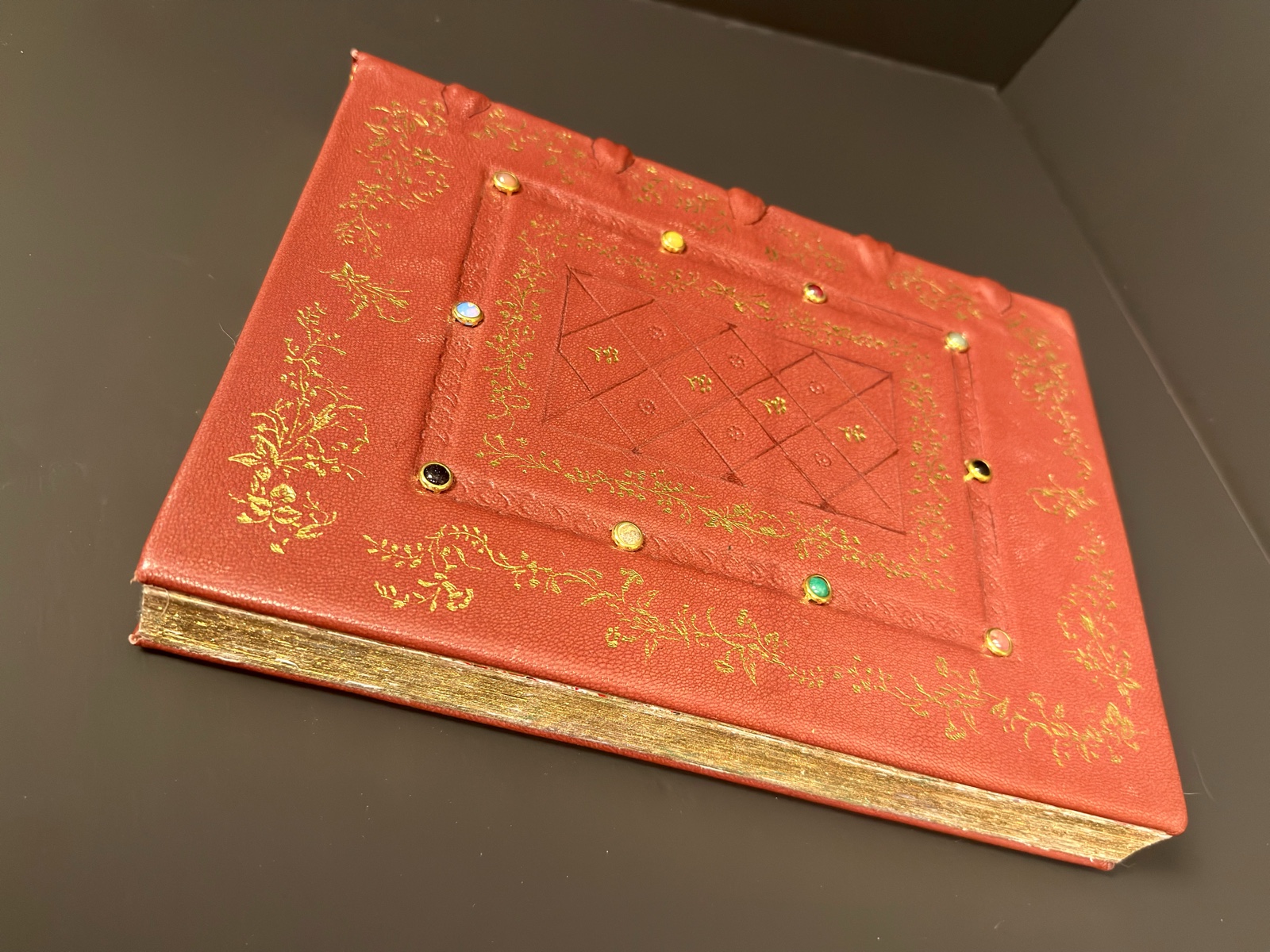 Top-angle view of the finished book — burnished gilt fore-edge alongside the gold-tooled front cover