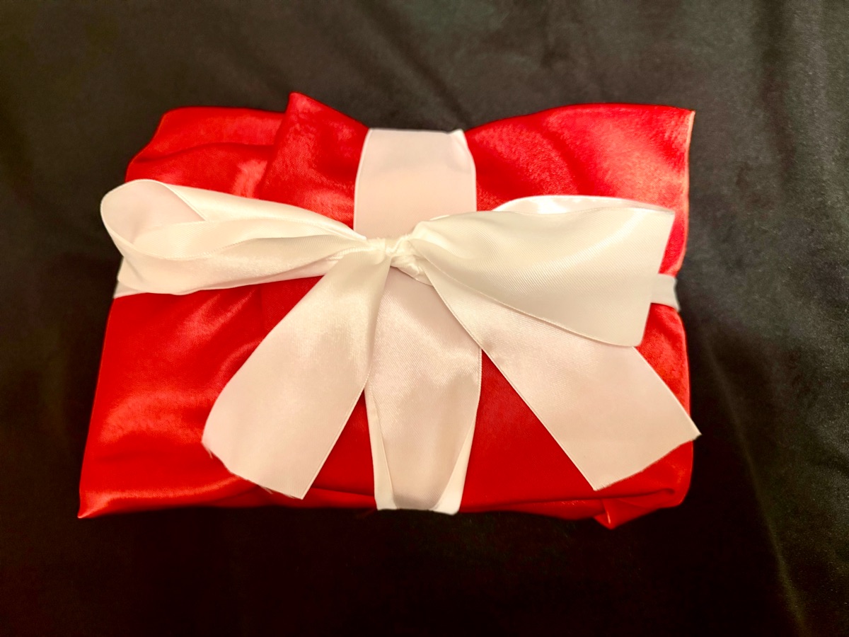 Red satin wrap tied with white ribbon, the packaging used for Martinist pieces.