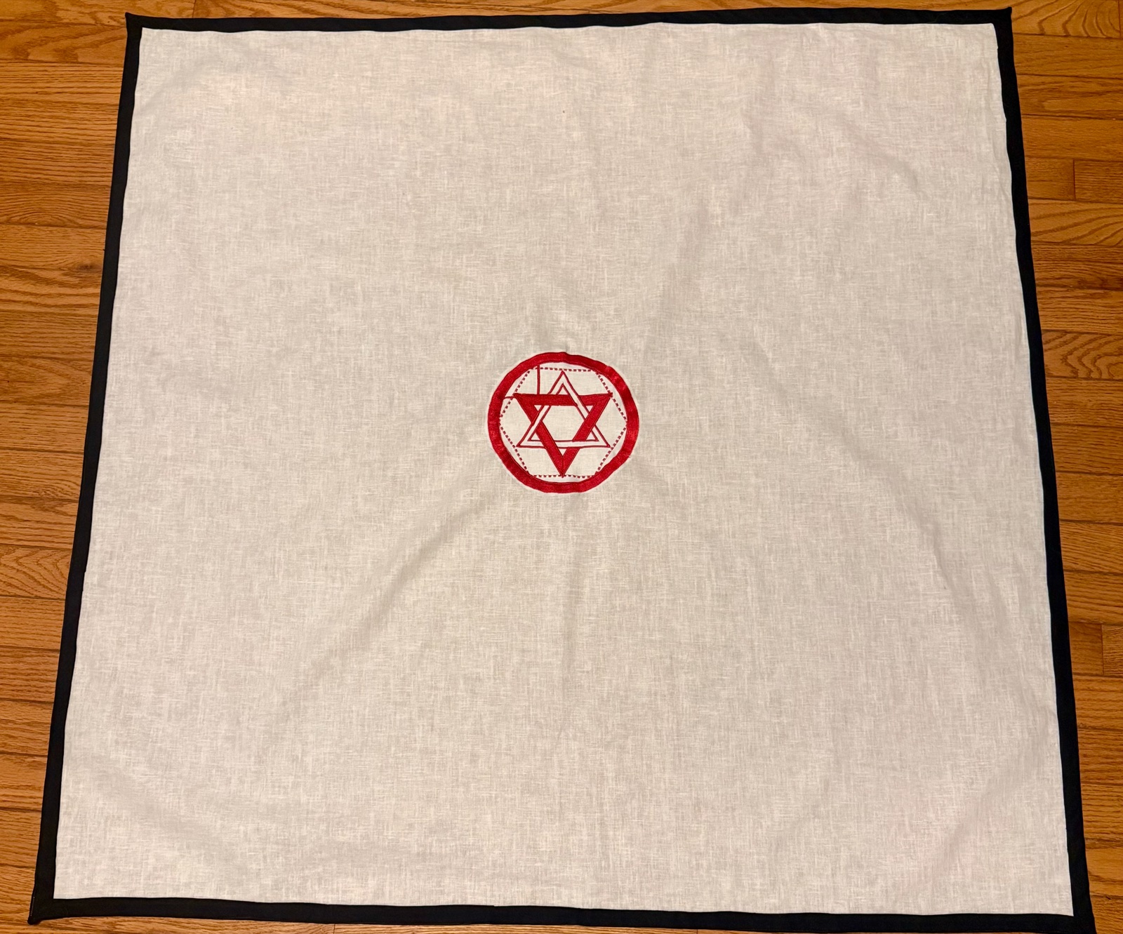 Martinist altar cloth in linen with a black trim border and a red embroidered pantacle at the centre.
